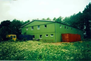 Grüne Lagerhalle umgeben von wilder, blühender Wiese