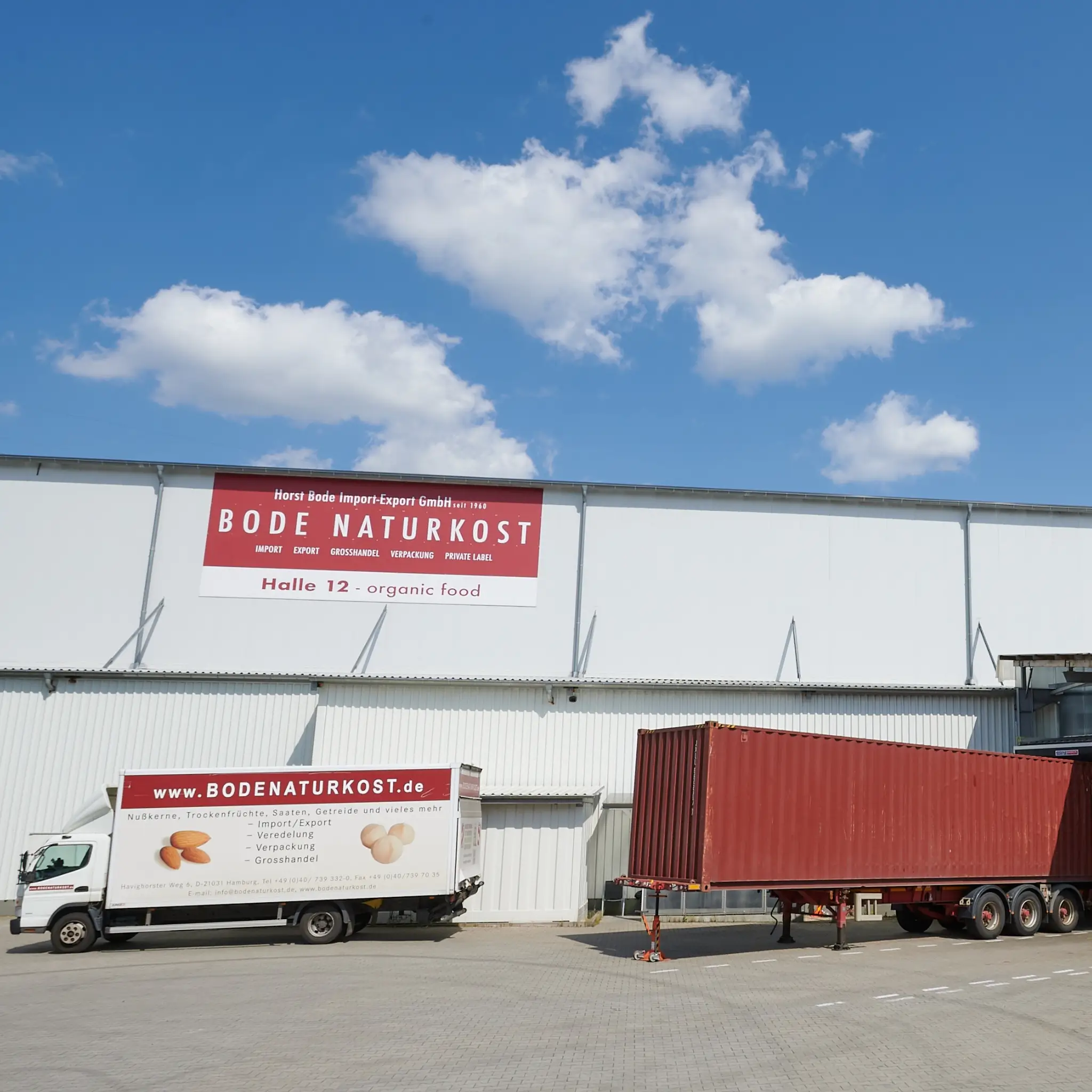 Außenansicht der Lagerhalle mit großem Bode Naturkost-Schild, davor steht ein LKW von Bode und ein Container zur Entladung